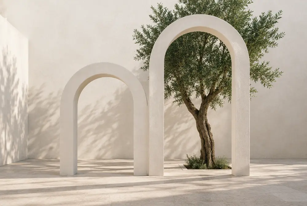 Two white arches, the right one taller, with an olive tree